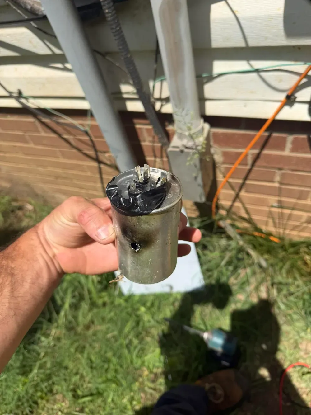 Close up of a burned capacitor with a hole blown through its casing, pulled from a Greenville system
