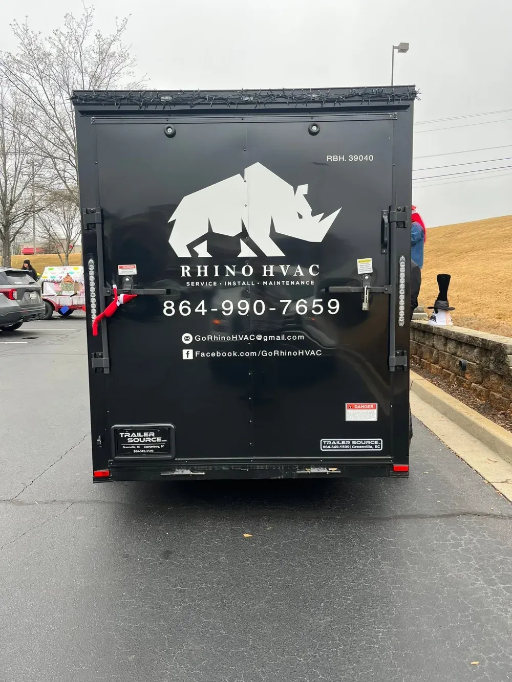 The Rhino HVAC service trailer parked in Simpsonville, string lights along its roofline, the rear door lettered with the company logo and phone number