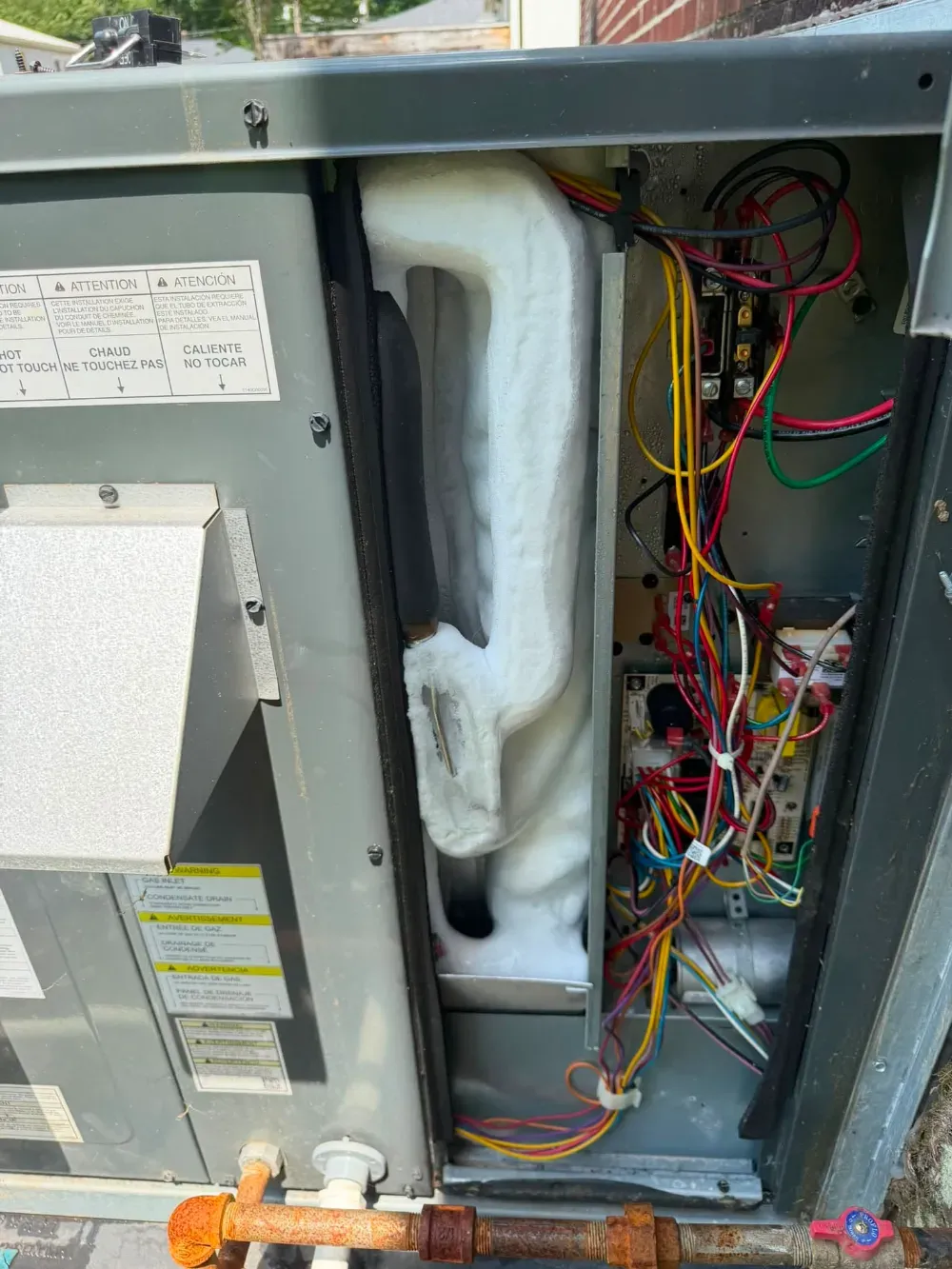 A frozen evaporator coil behind an open access panel in a Greenville home