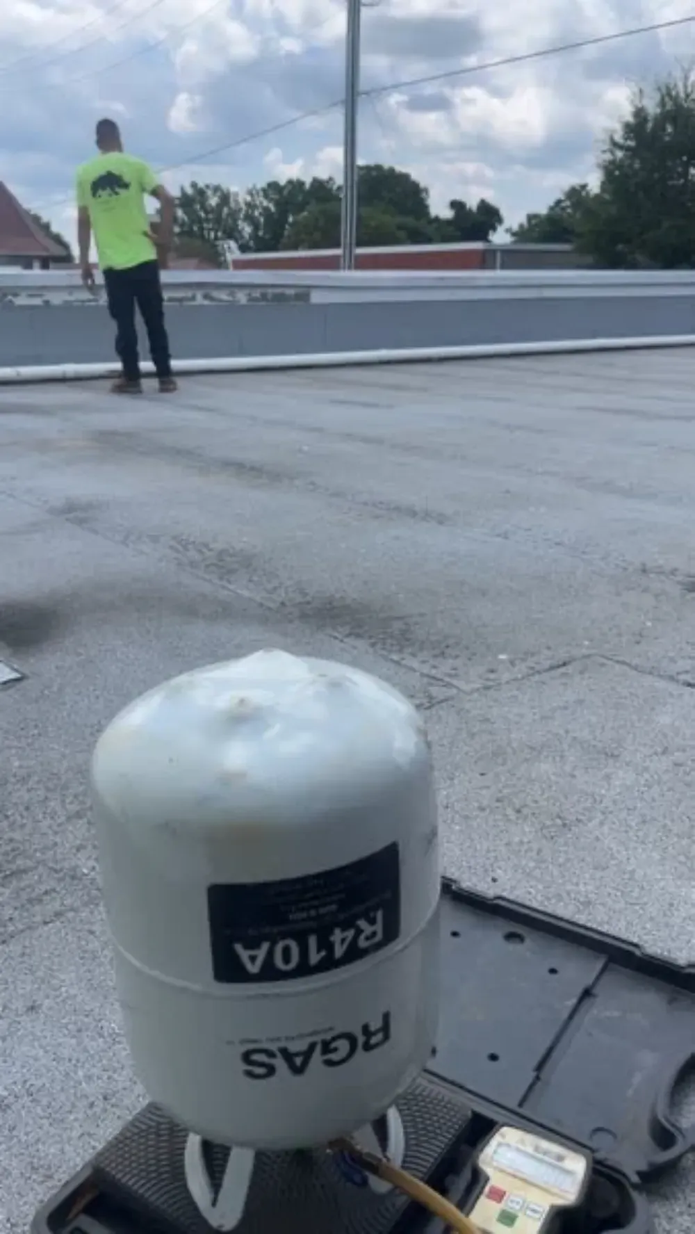 A refrigerant tank standing beside a rooftop unit during service in Greenville