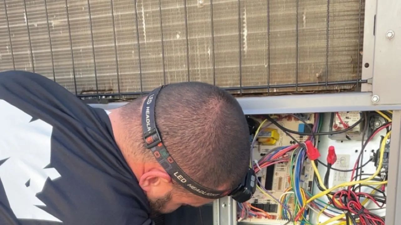 Rhino HVAC technician diagnosing the control board inside an open outdoor AC unit