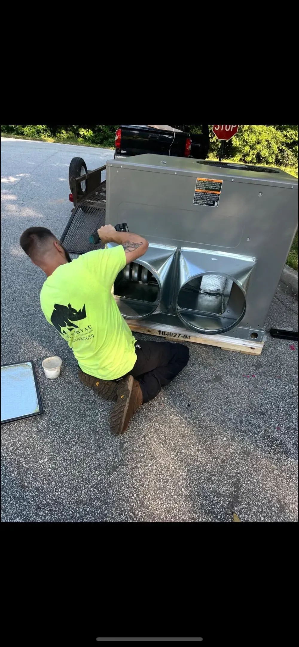 A Rhino HVAC technician assembling a package unit in a Simpsonville driveway