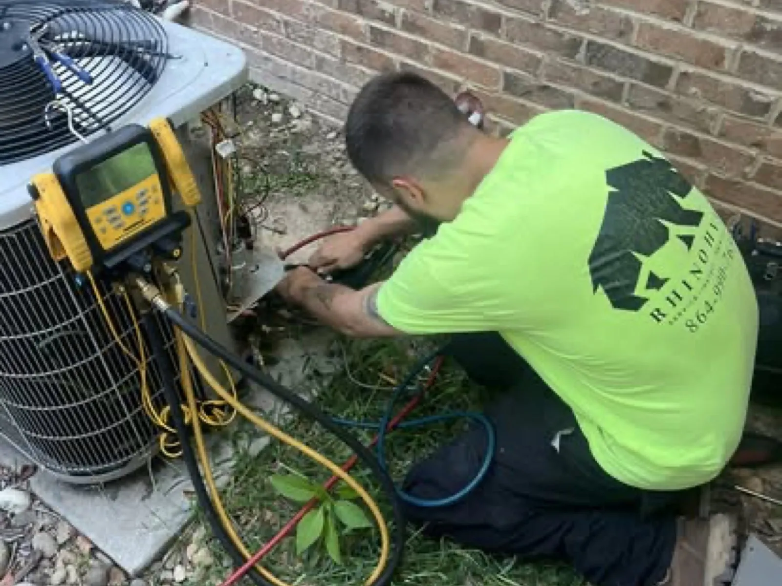 Rhino HVAC technician checking refrigerant gauges on an outdoor condenser unit