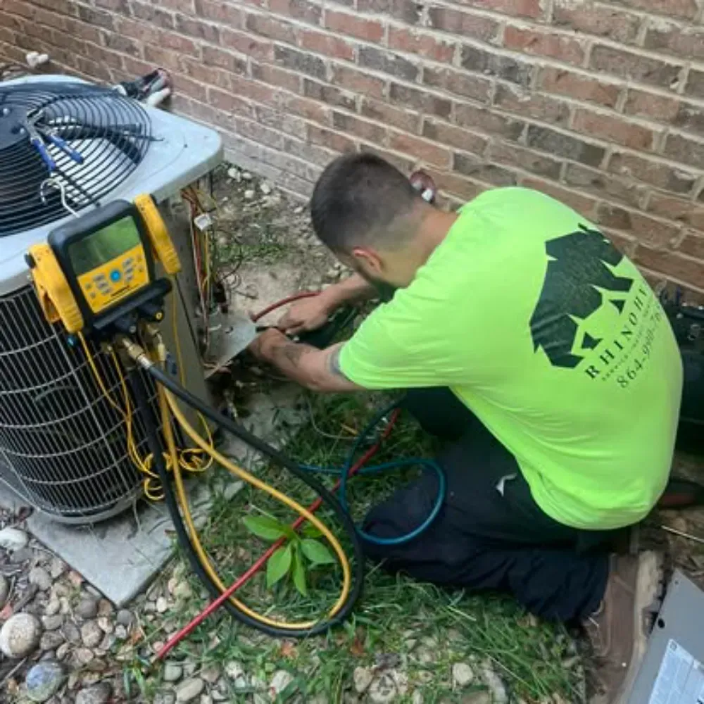 A Rhino HVAC technician connecting refrigerant gauges to a condenser at a Simpsonville home