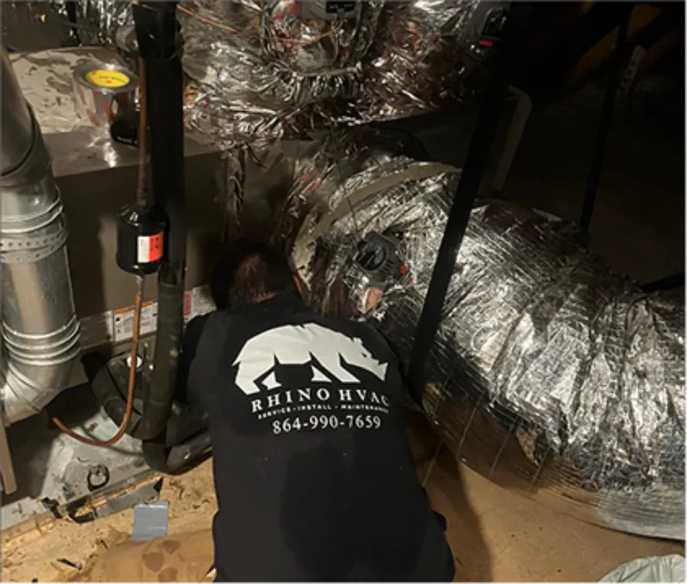 A Rhino HVAC technician inspecting ductwork in a Piedmont crawl space