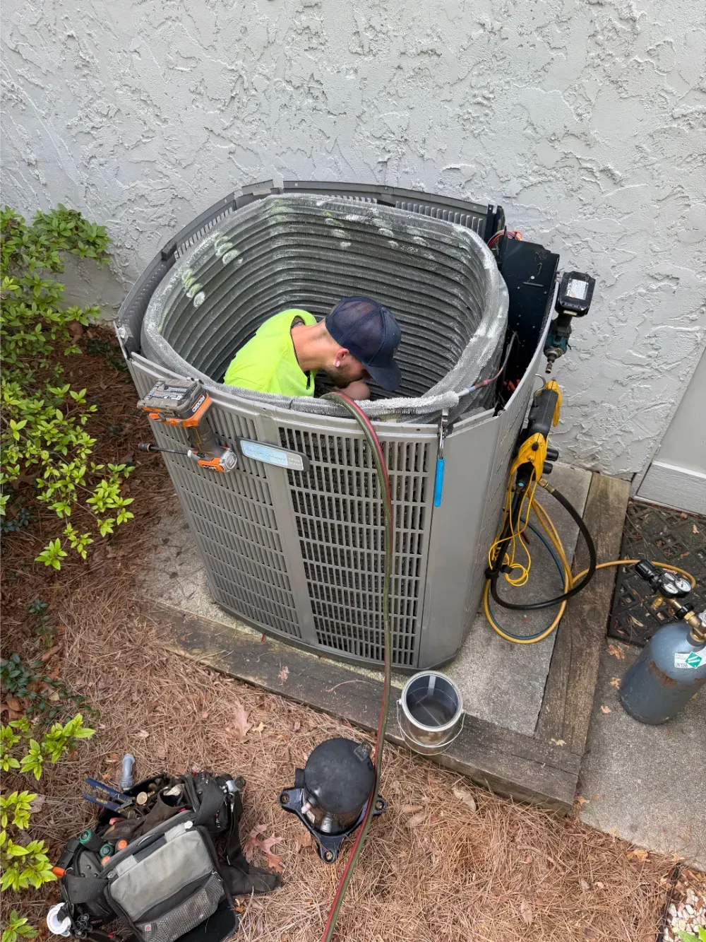 A Rhino HVAC technician working inside an open condenser cabinet in Belton