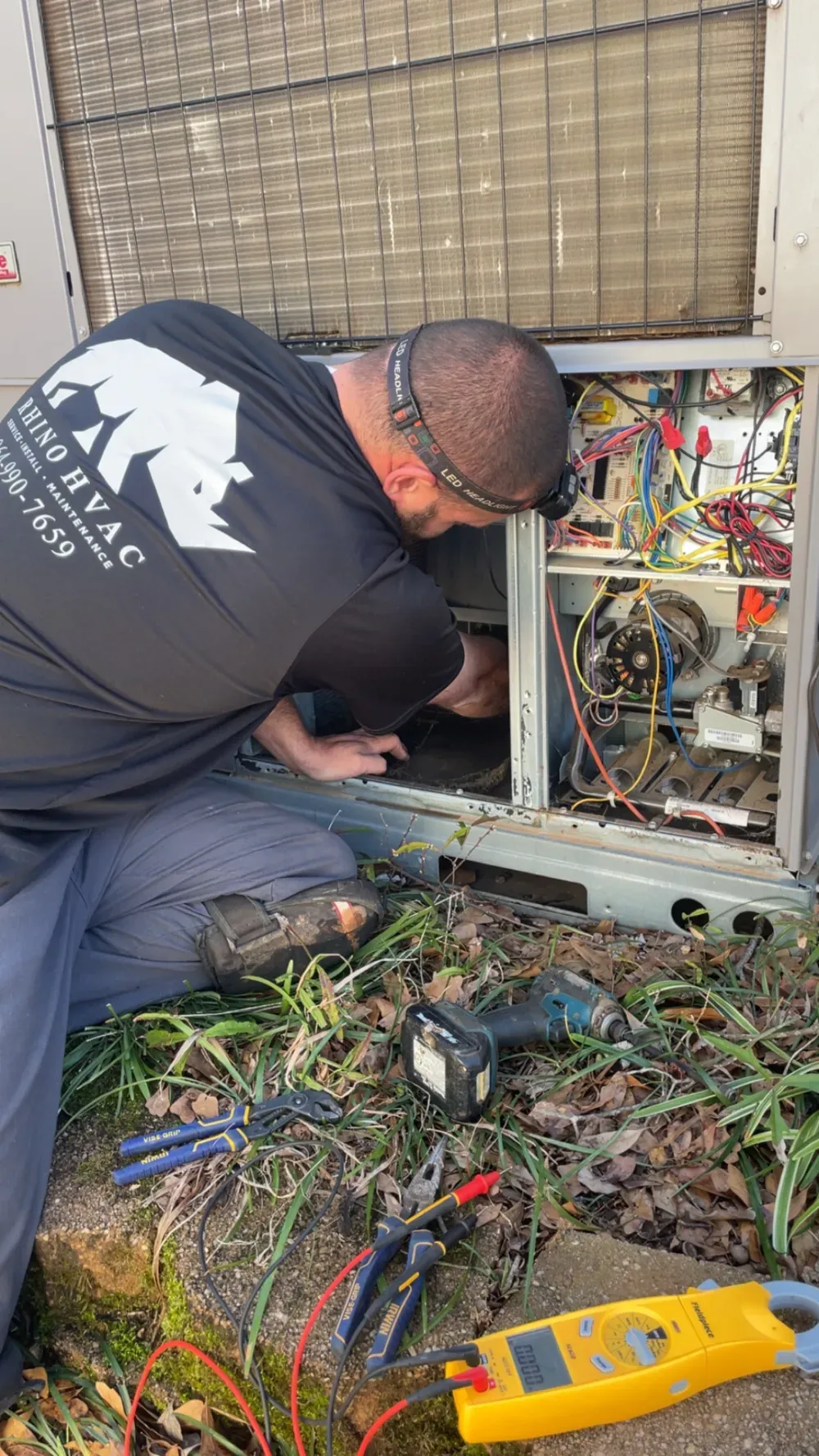 A Rhino HVAC technician repairing the control panel of a rooftop unit in Greenville