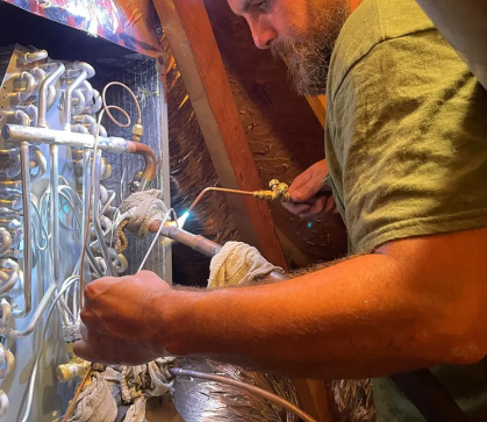 A Rhino HVAC technician soldering evaporator tubing in Piedmont