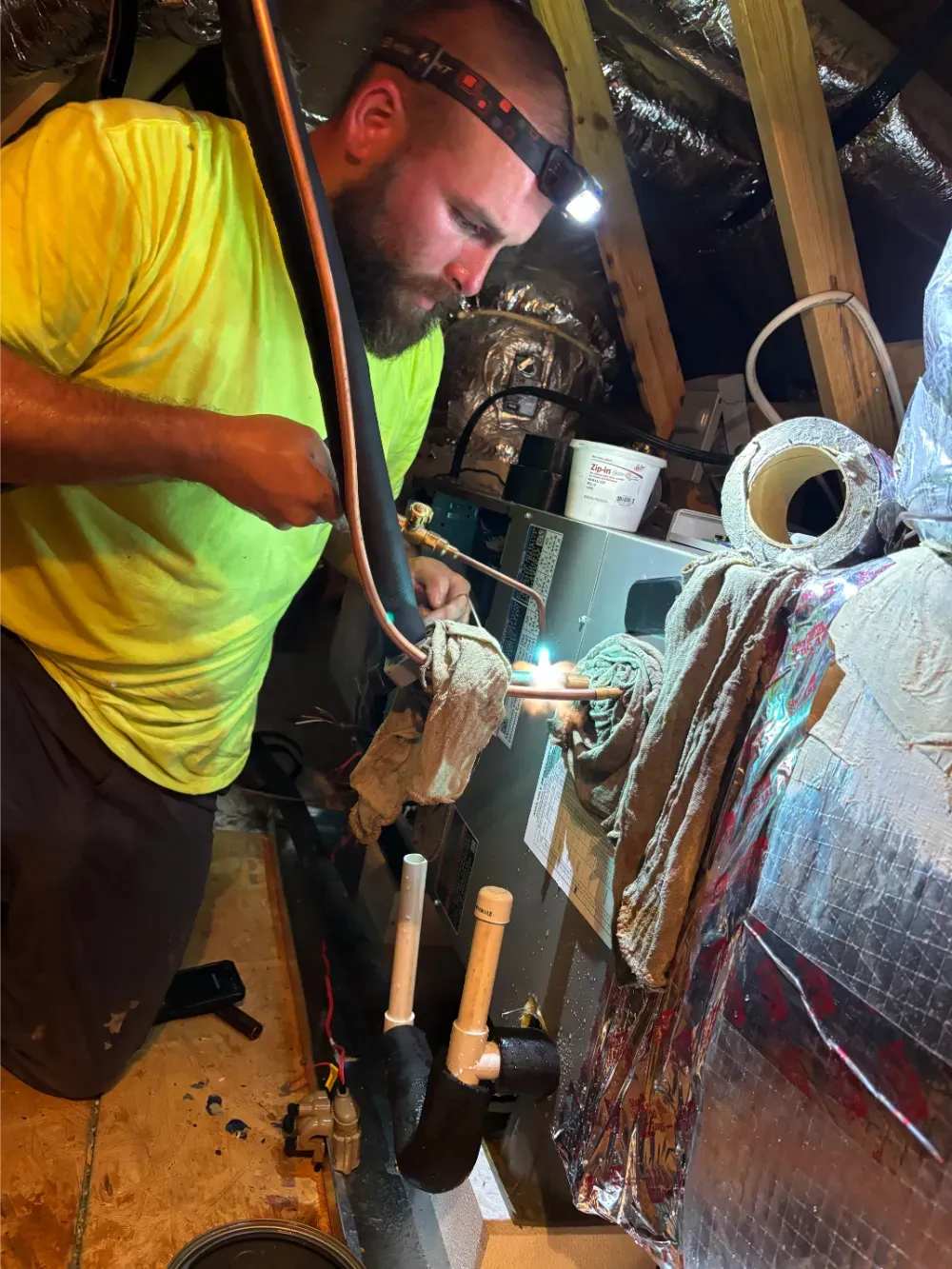A Rhino HVAC technician soldering pipework at an air handler in Greenville