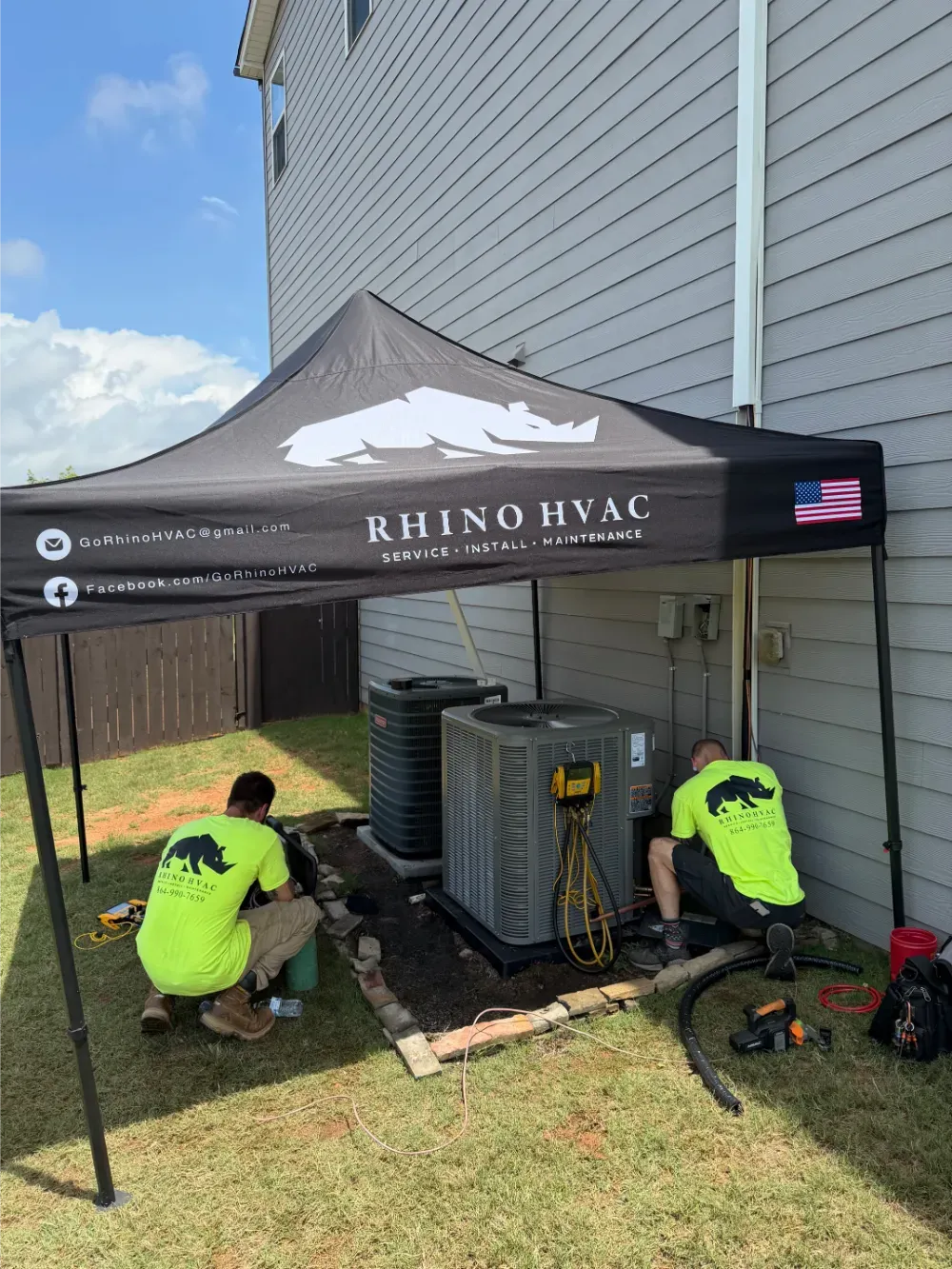 Rhino HVAC technicians working under a shade tent beside outdoor condensers in Easley