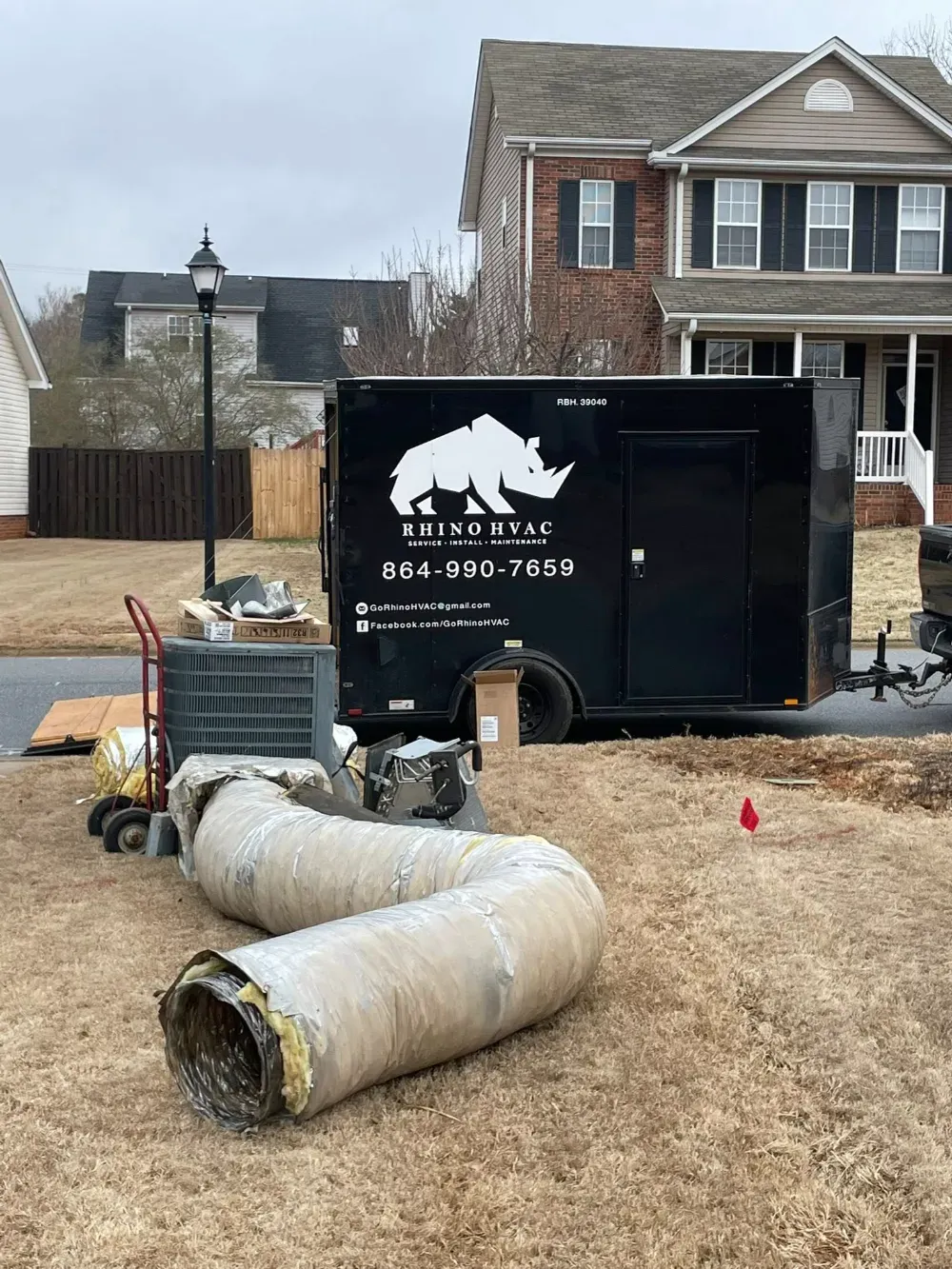 A removed condenser and old ductwork stacked beside the Rhino HVAC trailer in a Simpsonville driveway